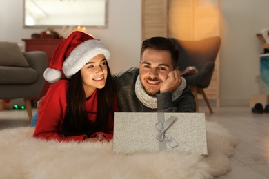Photo of Young couple with opened Christmas gift box at home