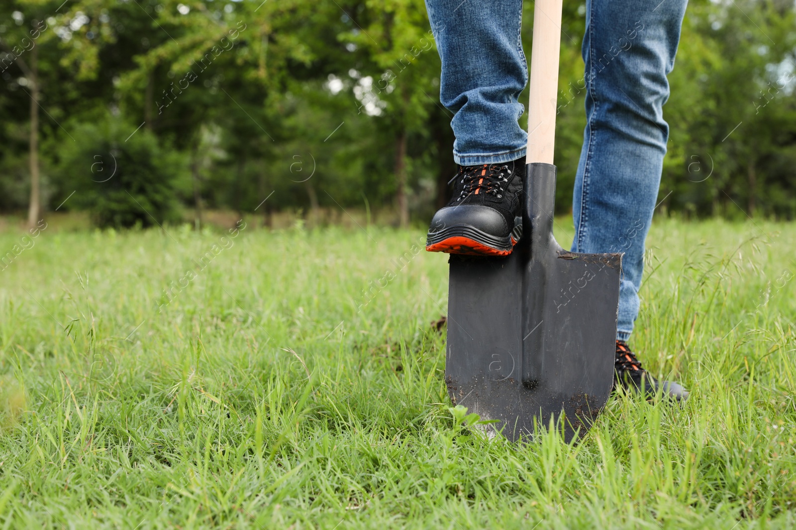 Photo of Worker digging soil with shovel outdoors, closeup