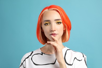 Beautiful young woman with bright dyed hair on turquoise background