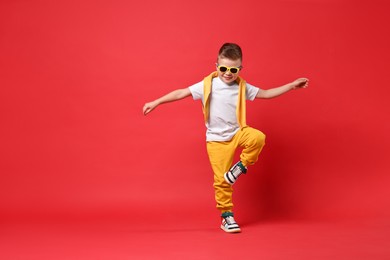 Happy little boy dancing on red background. Space for text