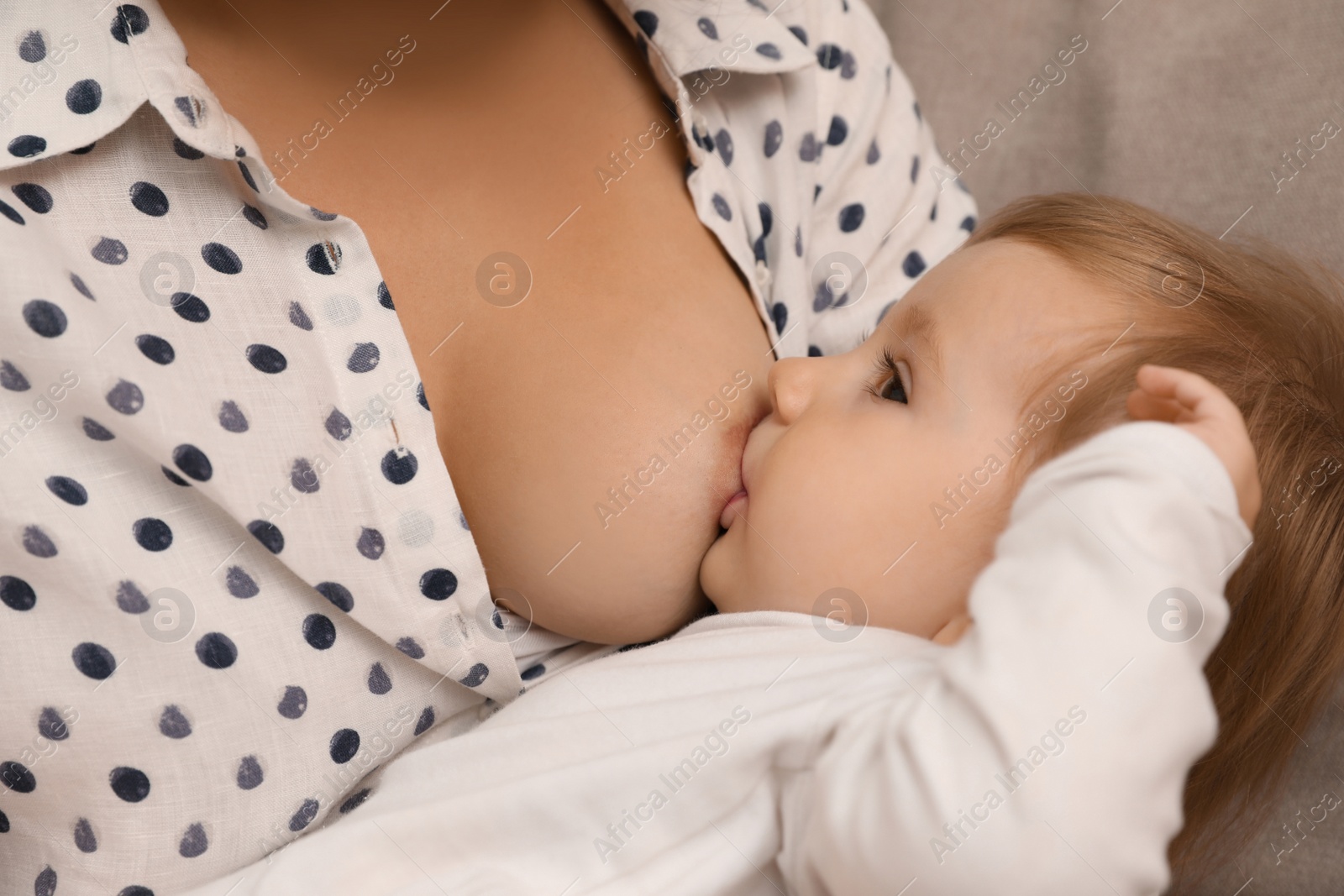 Photo of Woman breastfeeding her little baby at home, closeup