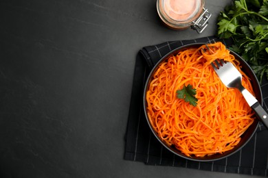 Photo of Delicious Korean carrot salad and parsley on black table, flat lay. Space for text