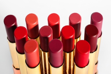 Photo of Set of bright lipsticks in gold tubes on white background