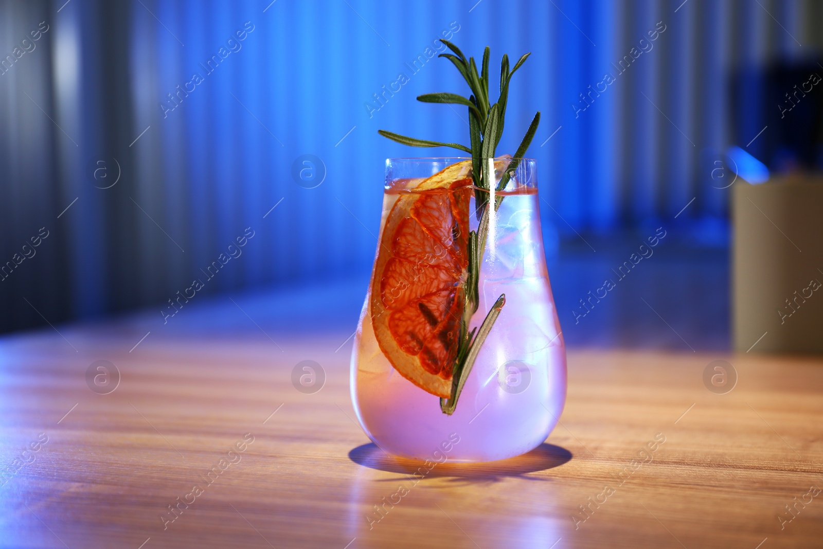 Photo of Glass of delicious cocktail with vodka on wooden counter in bar