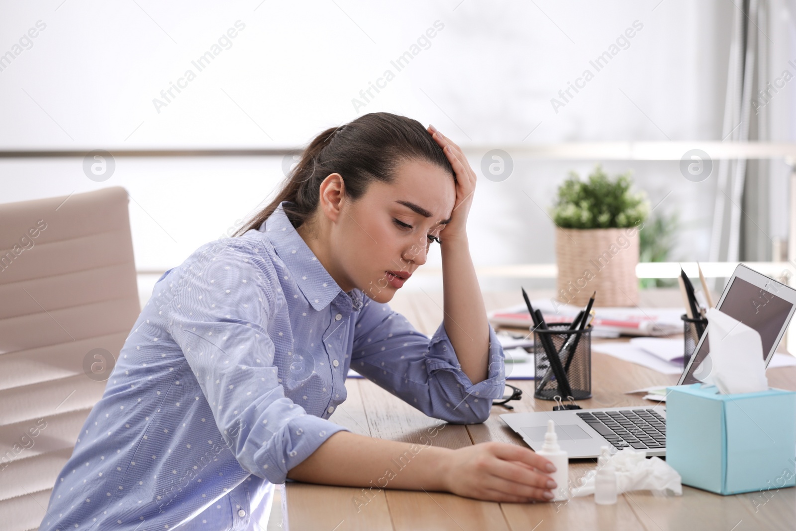 Photo of Sick young woman with nasal spray in office