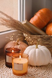 Photo of Scented candles and pumpkins on window sill indoors