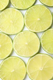 Photo of Fresh juicy lime slices on white background, flat lay