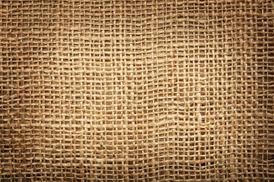 Texture of natural burlap fabric as background, top view. Vignette effect 