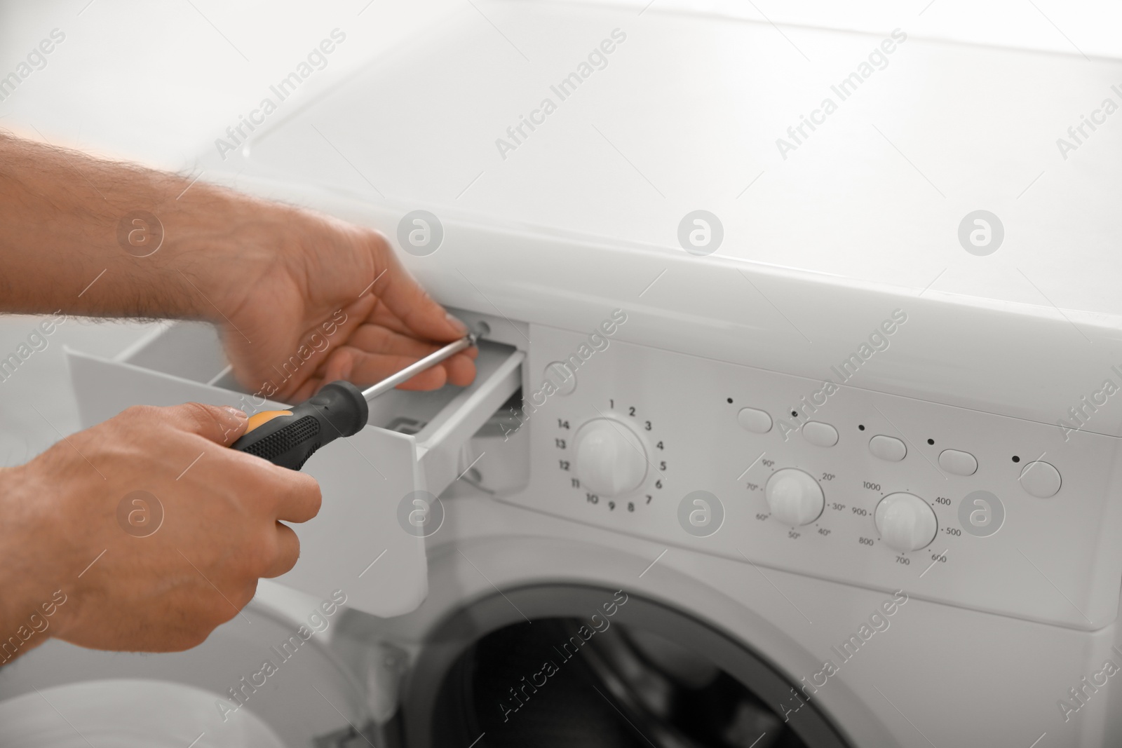 Photo of Professional plumber repairing broken washing machine, closeup