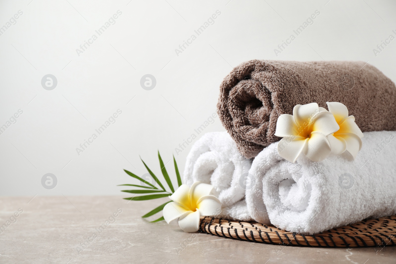 Photo of Beautiful spa composition with plumeria flowers on grey marble table against light background. Space for text