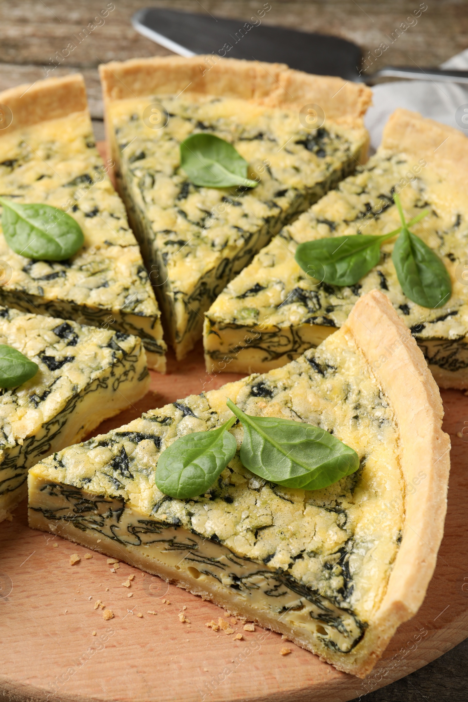 Photo of Cut delicious spinach pie on wooden board, closeup