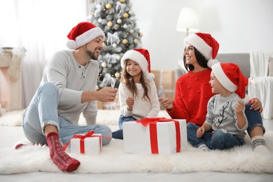 Photo of Happy family with children and Christmas gifts on floor at home