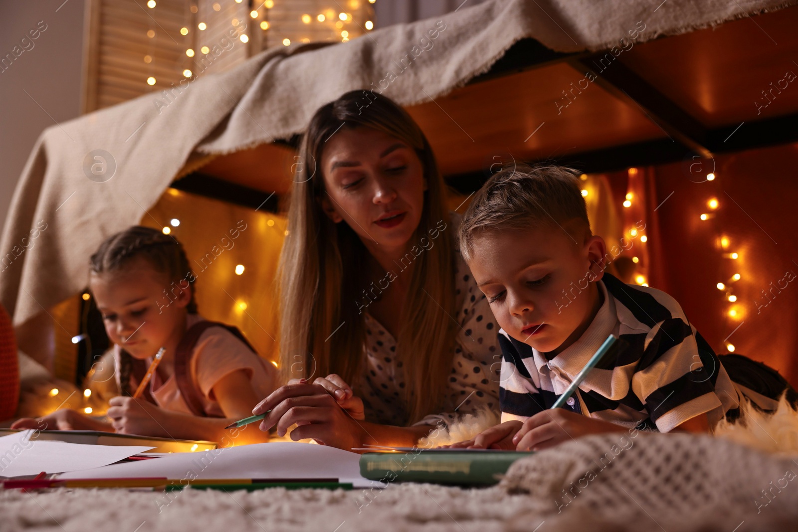 Photo of Mother and her children drawing in play tent at home