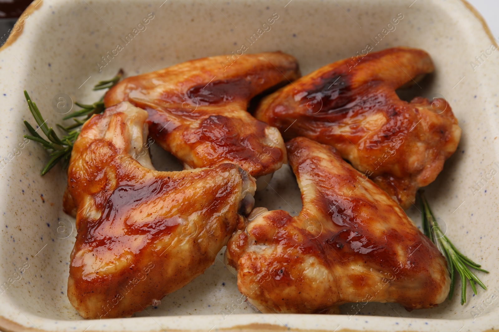 Photo of Fresh marinated chicken wings and rosemary in baking dish, closeup