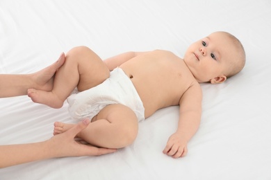 Photo of Mother and her cute child on white bed. Baby massage and exercises