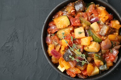 Photo of Dish with tasty ratatouille on black table, top view. Space for text