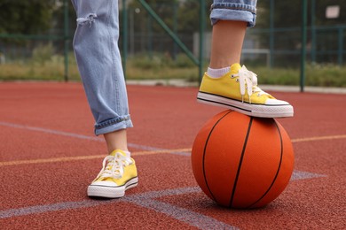 Woman with basketball ball wearing yellow classic old school sneakers on court outdoors, closeup