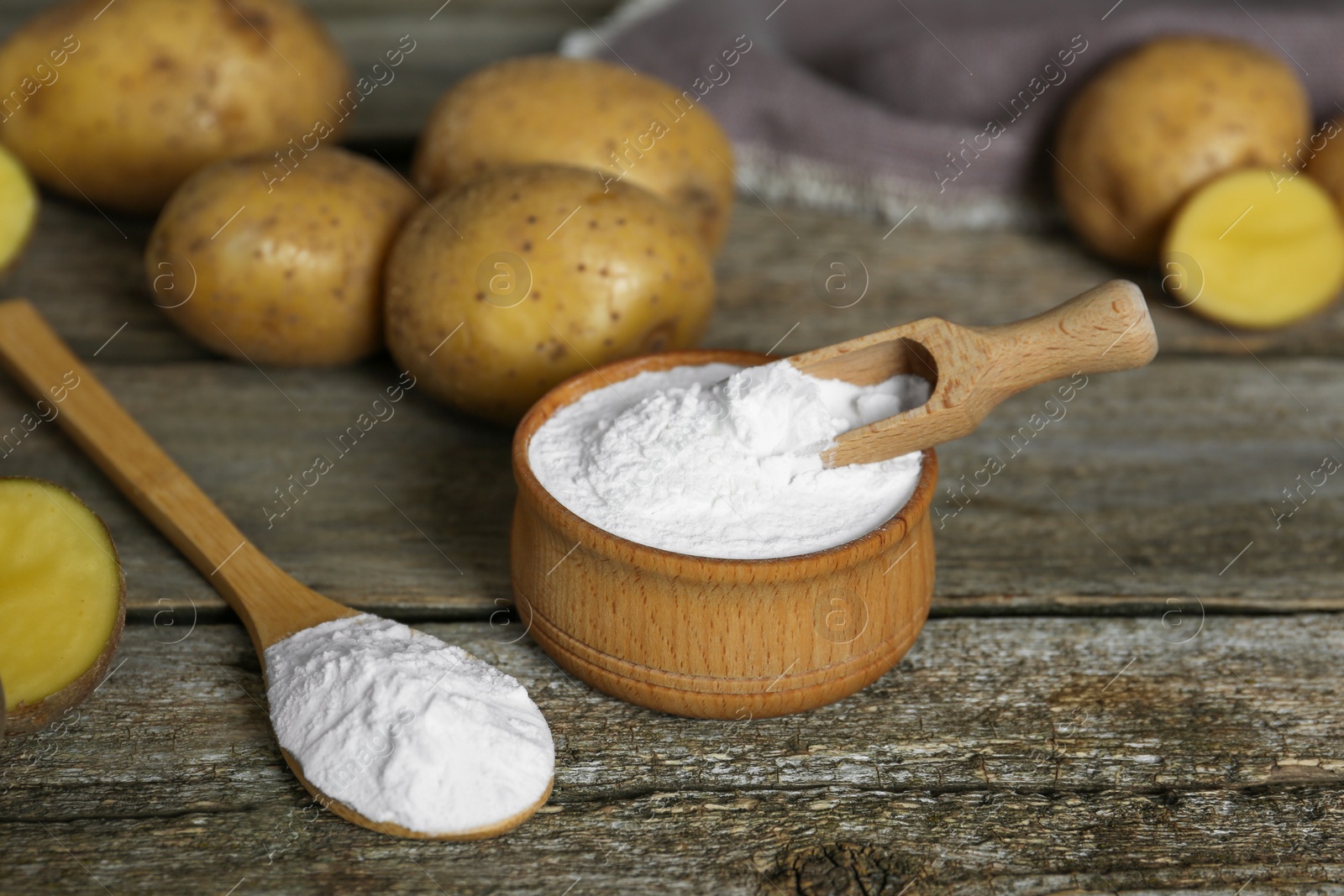 Photo of Starch and fresh raw potatoes on wooden table