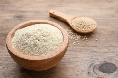 Photo of Quinoa flour in bowl and spoon with seeds on wooden table