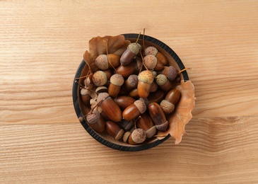 Acorns and oak leaves on wooden table, top view