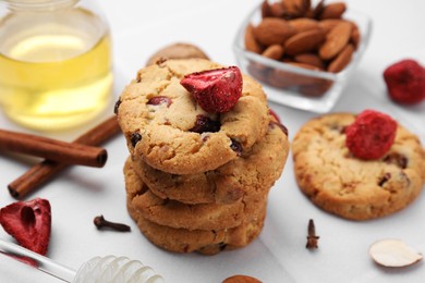 Photo of Cookies with freeze dried fruits, cinnamon, honey and nuts on white tiled table, closeup