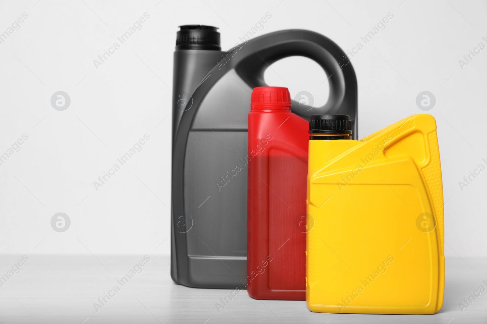 Photo of Motor oil in different canisters on table against white background, space for text