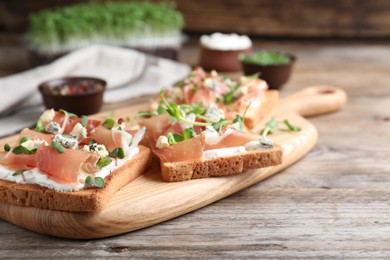 Photo of Delicious sandwiches with prosciutto, cheese and microgreens on wooden table. Space for text