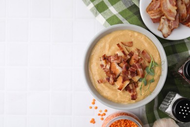 Delicious lentil soup with bacon and other ingredients on white tiled table, top view. Space for text