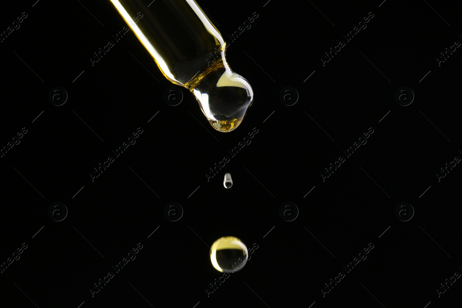 Photo of Dripping tincture from pipette on black background, closeup