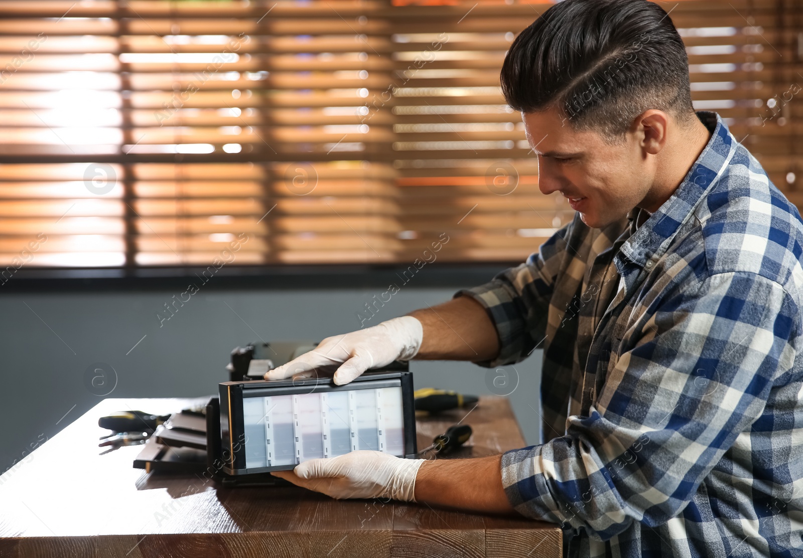 Photo of Professional repairman fixing modern printer in office