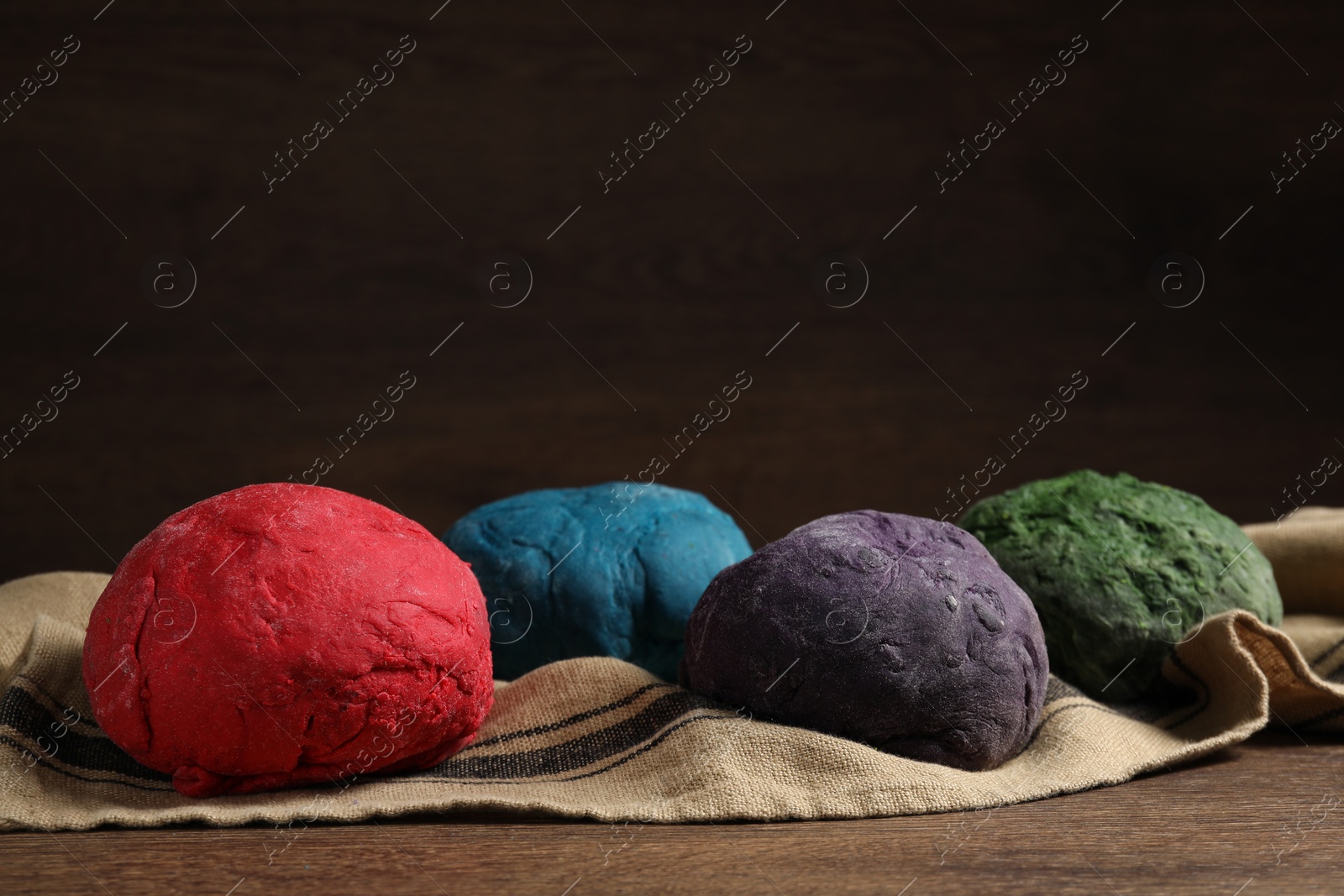 Photo of Dough painted with food colorings on wooden table, space for text