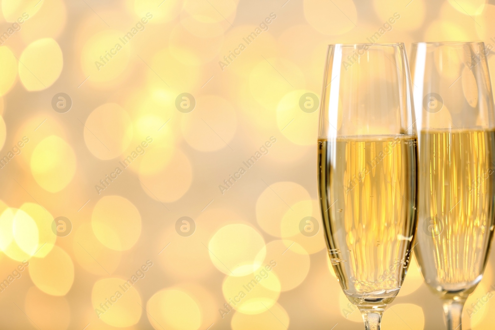 Photo of Glasses of champagne against blurred lights. Space for text