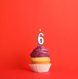 Photo of Birthday cupcake with number six candle on red background