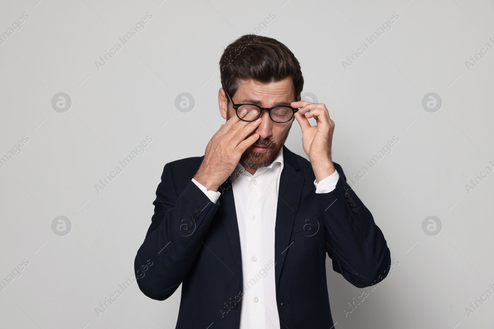 Photo of Man suffering from eyestrain on light grey background