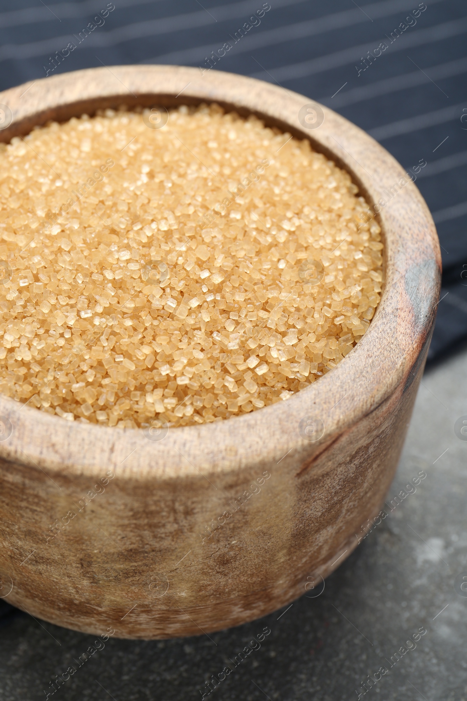 Photo of Brown sugar in bowl on grey textured table, closeup