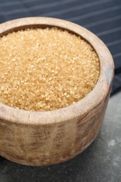 Brown sugar in bowl on grey textured table, closeup