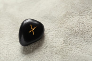 Photo of Black stone rune Gebo on leather, closeup. Space for text