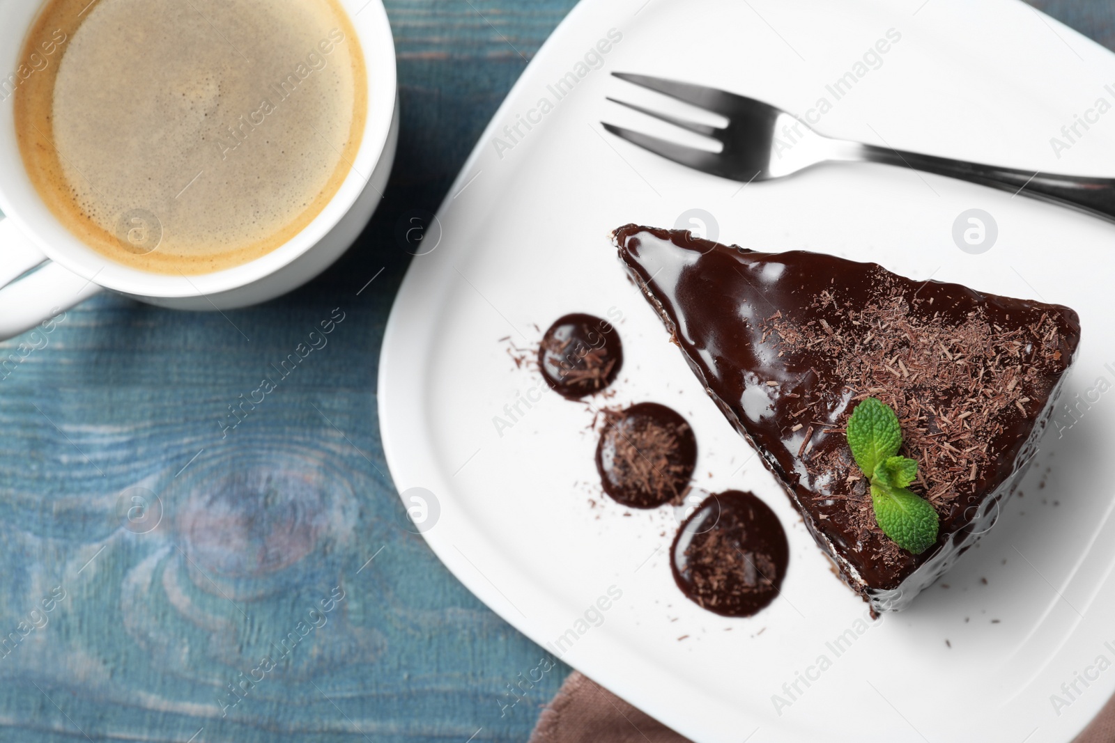 Photo of Delicious chocolate cake with mint on light blue wooden table, flat lay