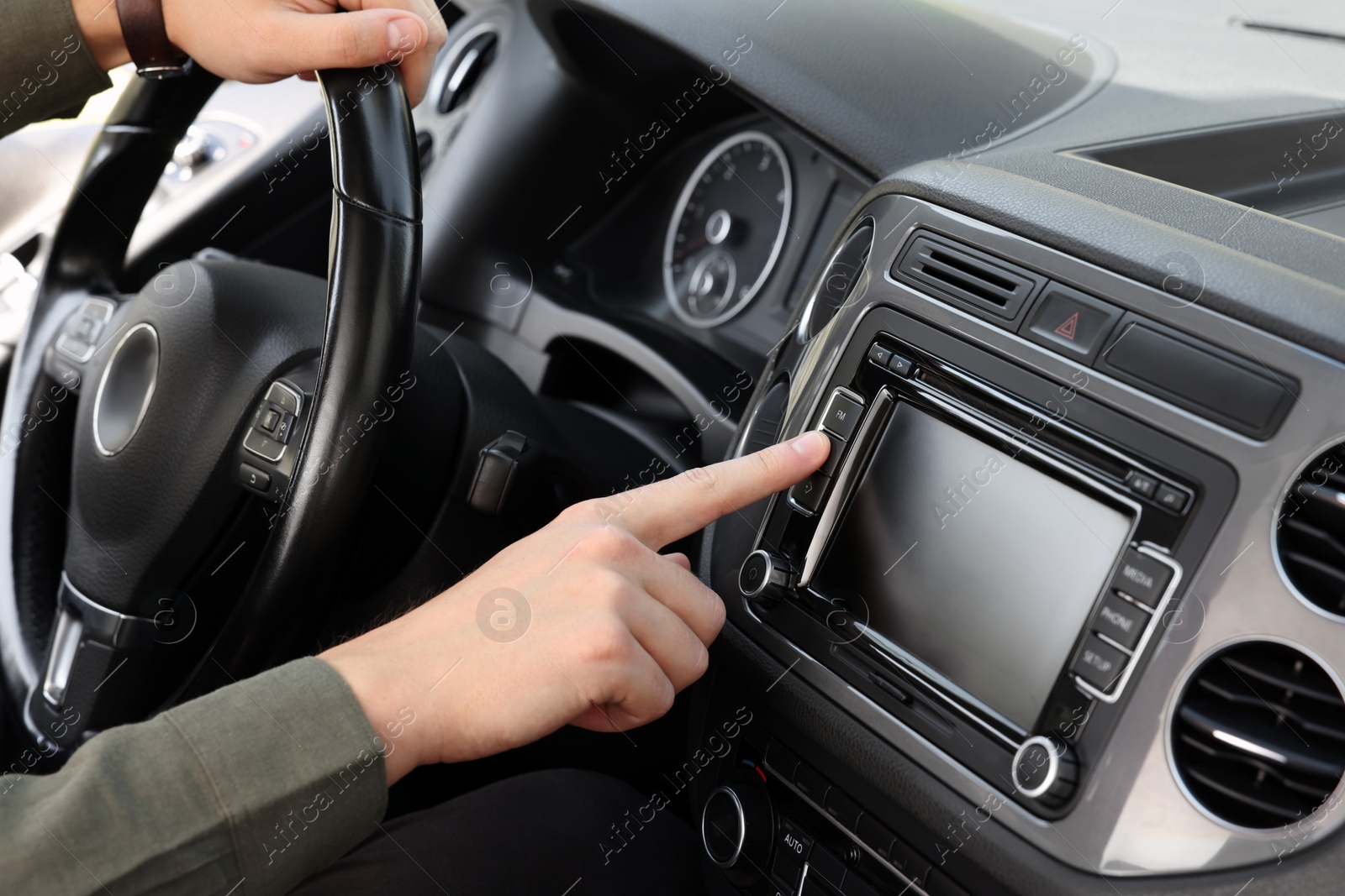 Photo of Choosing favorite radio. Man pressing button on vehicle audio in car, closeup