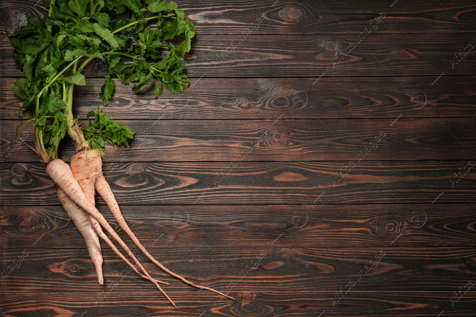 Photo of Tasty fresh ripe parsnips on wooden table, flat lay. Space for text