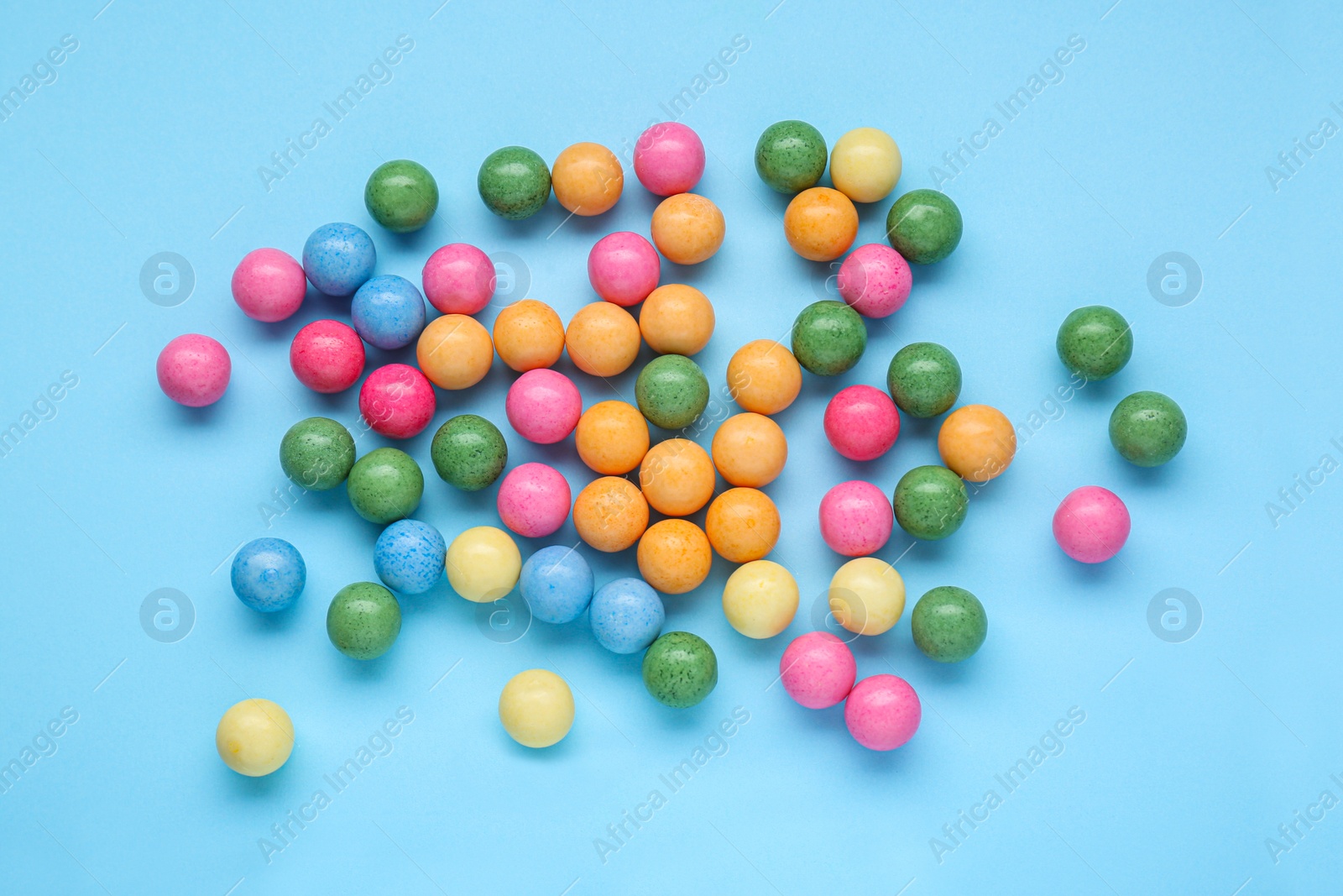 Photo of Many bright gumballs on light blue background, flat lay