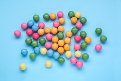 Photo of Many bright gumballs on light blue background, flat lay