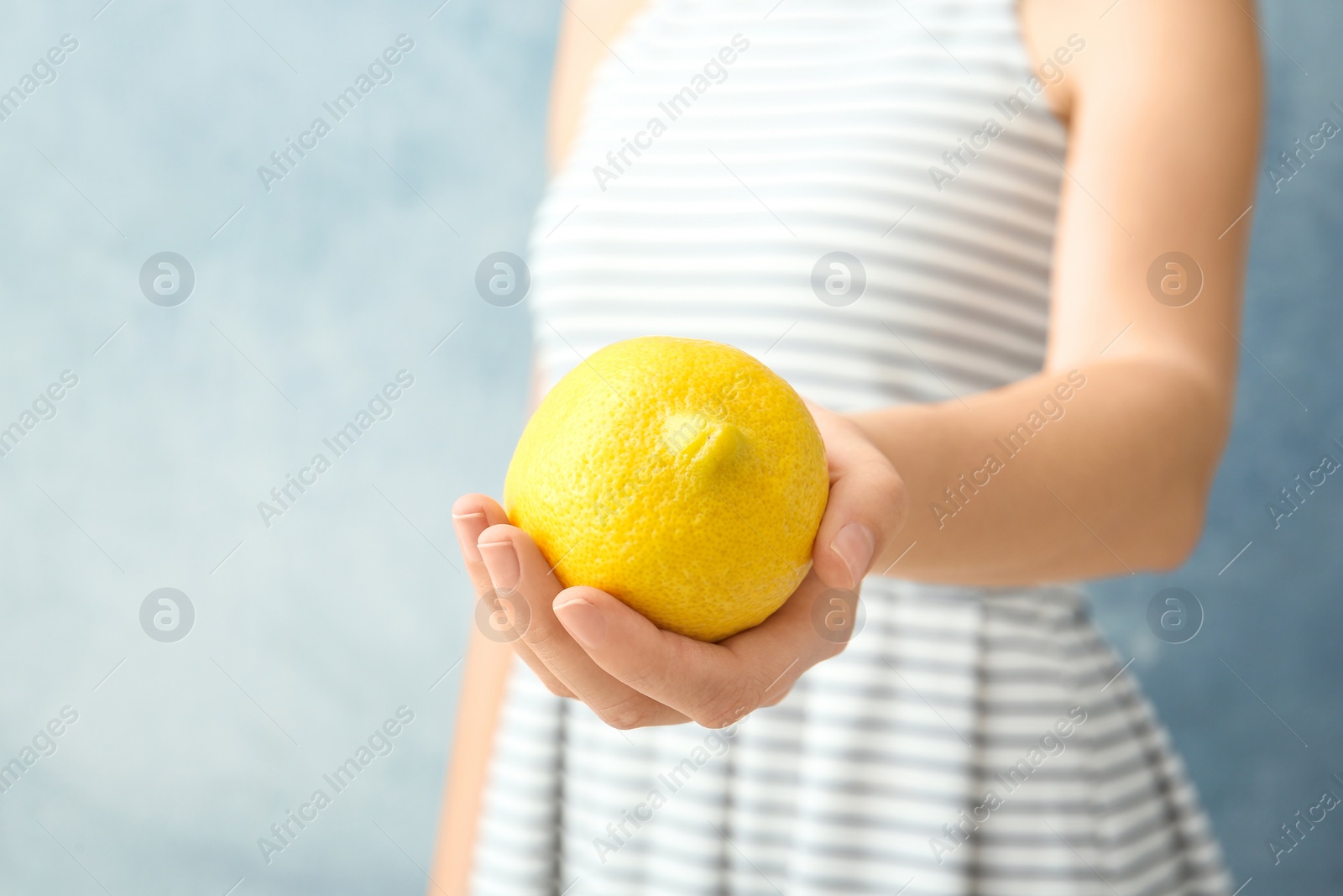 Photo of Woman holding ripe lemon against color background, closeup