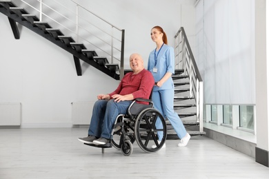 Nurse assisting senior man in wheelchair at hospital