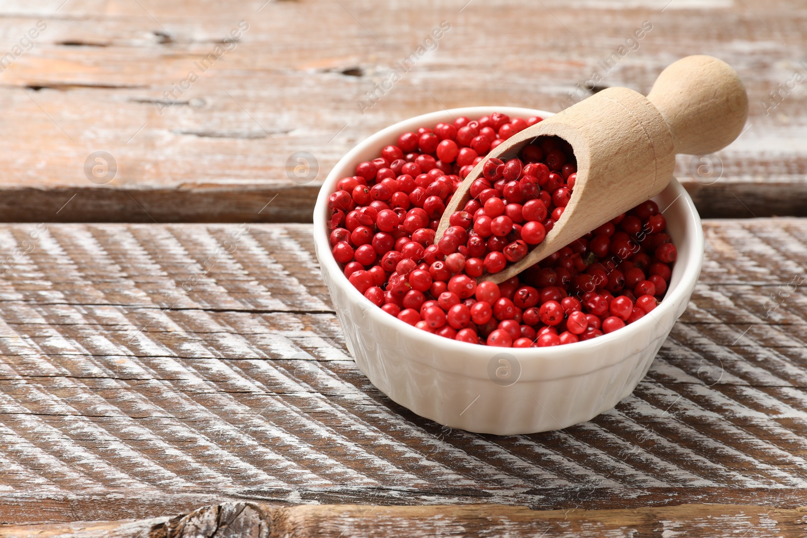 Photo of Aromatic spice. Red pepper in bowl and scoop on wooden table, closeup. Space for text