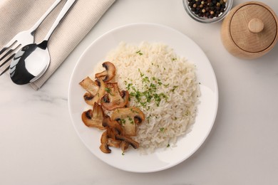 Photo of Delicious rice with parsley and mushrooms served on white marble table, flat lay