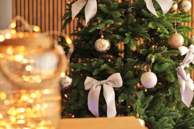 Photo of Christmas tree with stylish decor and fairy lights indoors