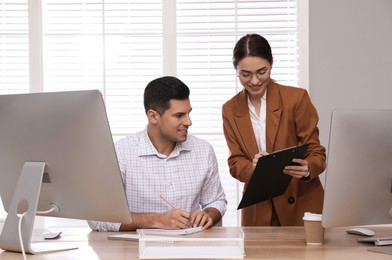 Businesswoman helping intern with work in office