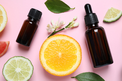 Photo of Flat lay composition with bottles of citrus essential oil on pink background