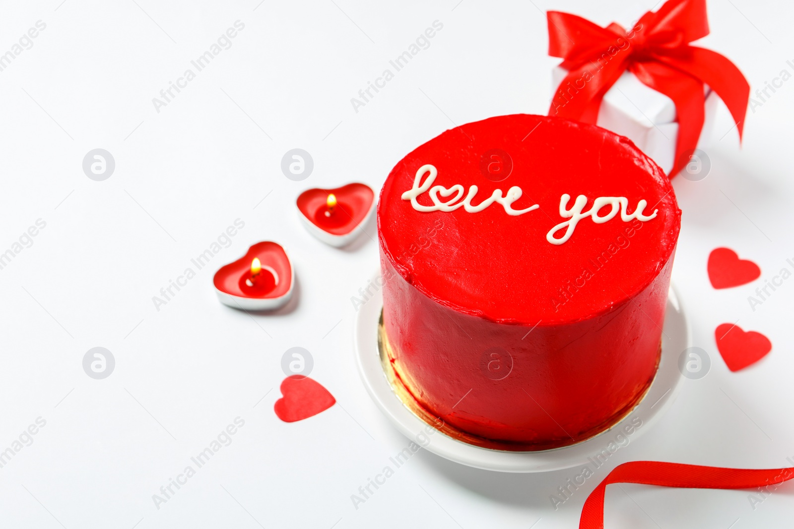 Photo of Bento cake with text Love You, candles, gift box and paper hearts on white table, space for text. St. Valentine's day surprise